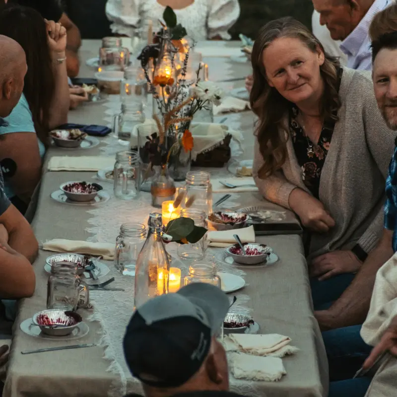 Guests smiling down the length of a candlelit table after dessert