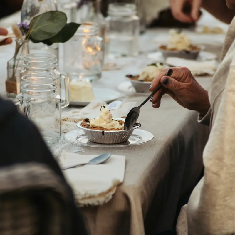 A guest eating dessert at a candlelit table set with mason jars
